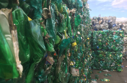 Muur van verwerkte petflessen samengedrukt tot blokken plastic.