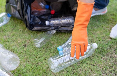 Persoon met handschoen die zwerfvuil opraapt.