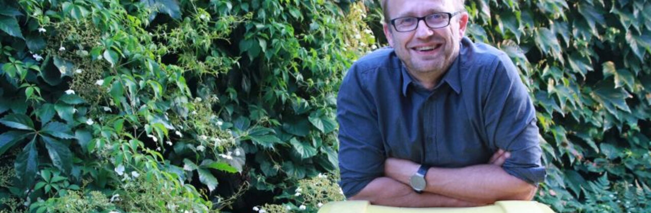 Man die leunt op gele vuilbak.