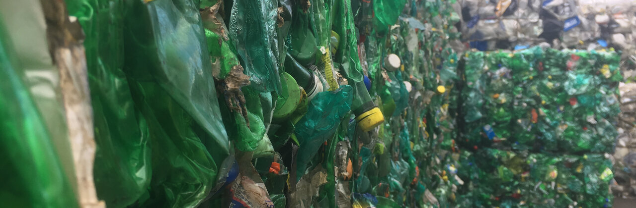 Muur van verwerkte petflessen samengedrukt tot blokken plastic.